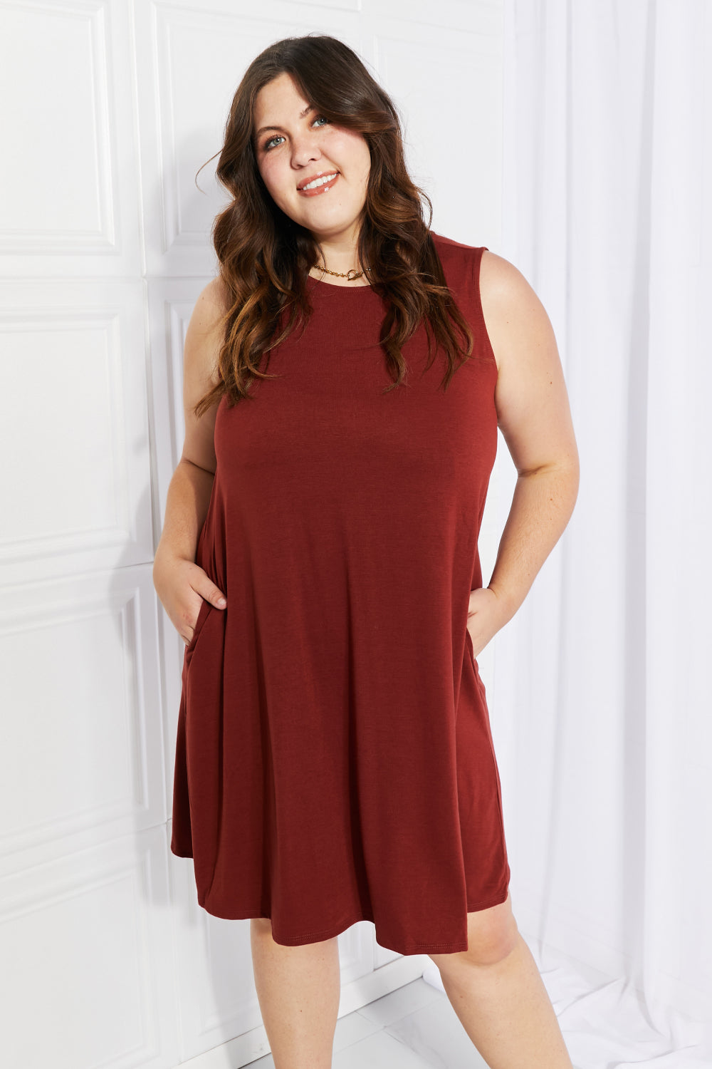 A stylish sleeveless dress in a solid color, featuring a flowy shift cut and pockets, perfect for spring and summer wear.