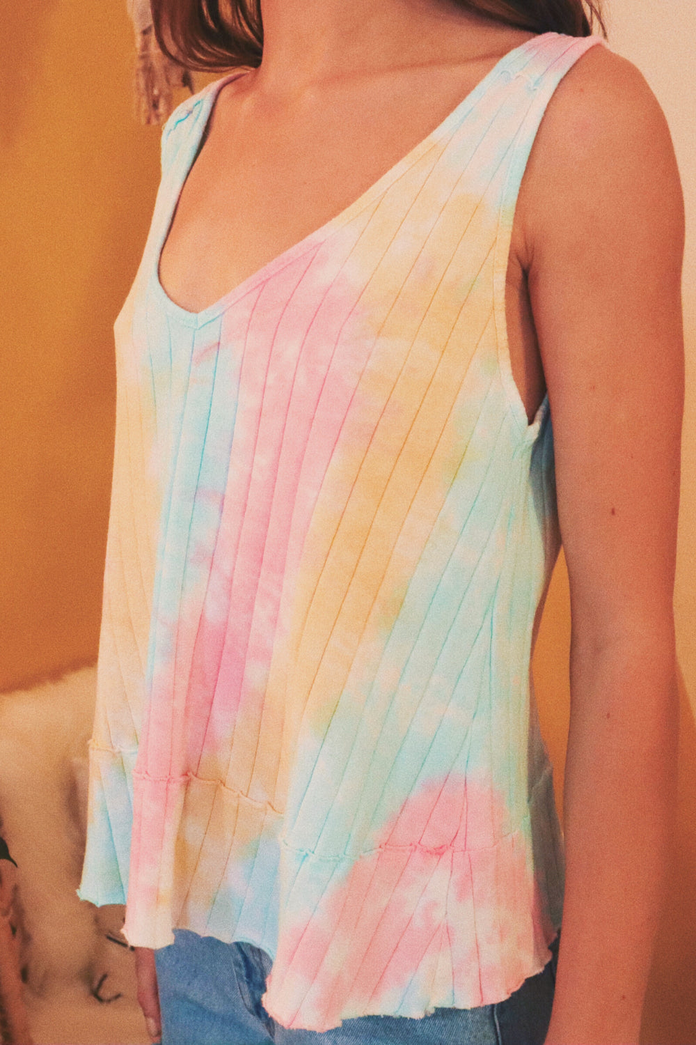 The Billie Tie-Dye tank top featuring a vibrant Miami tie-dye pattern, made from 100% organic cotton, styled casually over a tank.