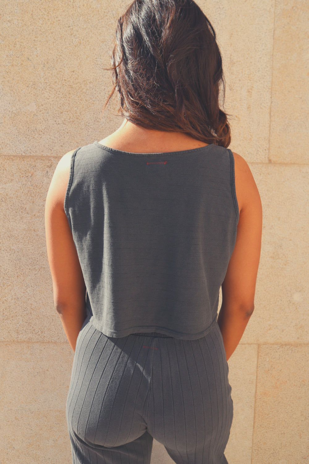 The Easy Tank in washed black and vintage white, showcasing its stylish peek-a-boo mid drift design, made from 100% organic cotton.