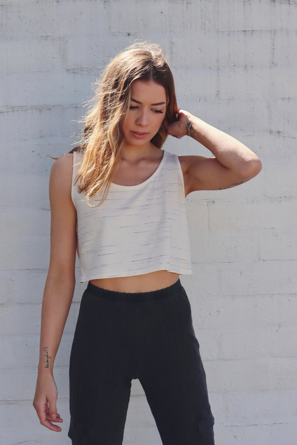 The Easy Tank in washed black and vintage white, showcasing its stylish peek-a-boo mid drift design, made from 100% organic cotton.