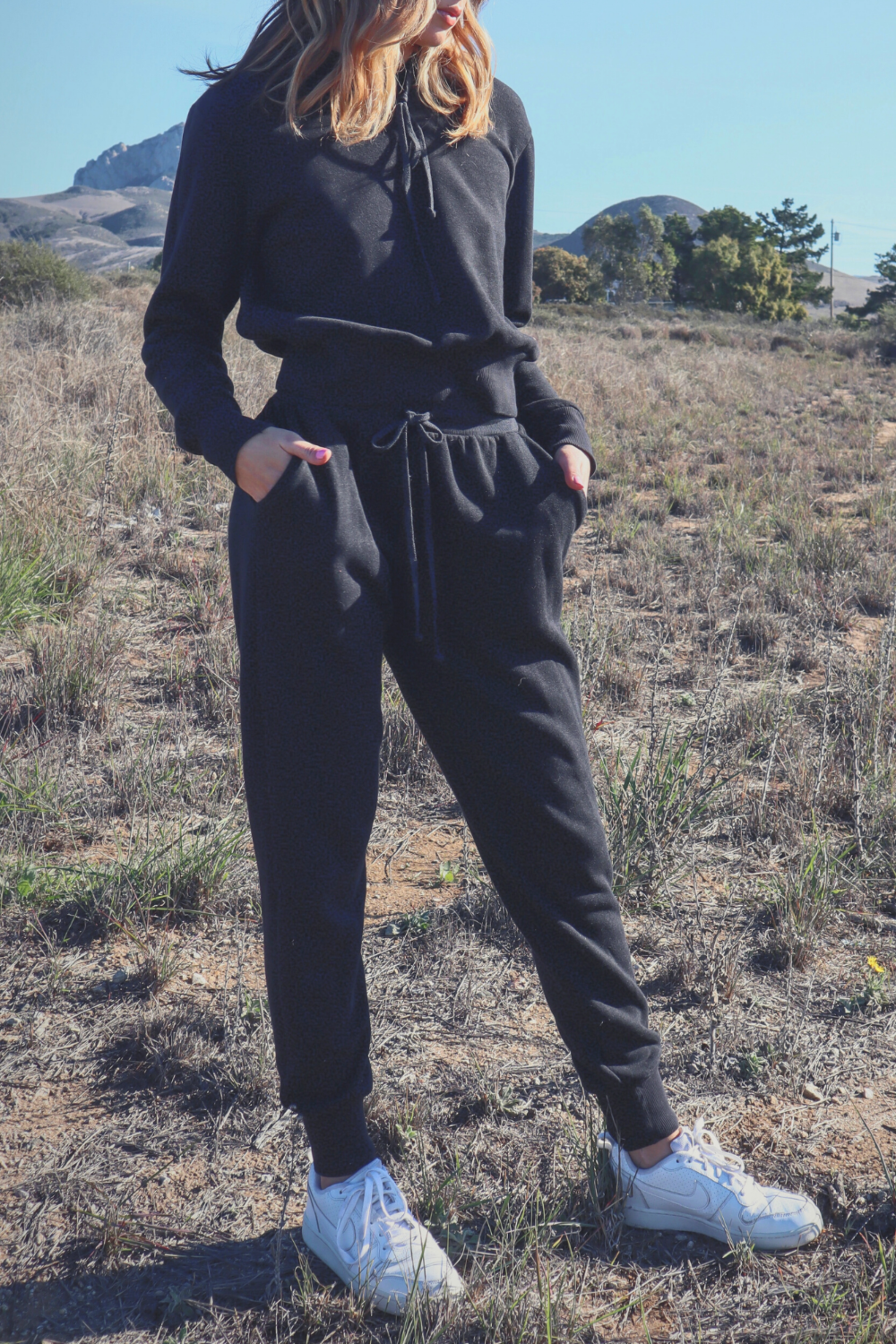 A pair of The New Daybreak Joggers in black, featuring a high waist, elastic ankle detail, and pockets, styled with a matching Daybreak Hoodie.