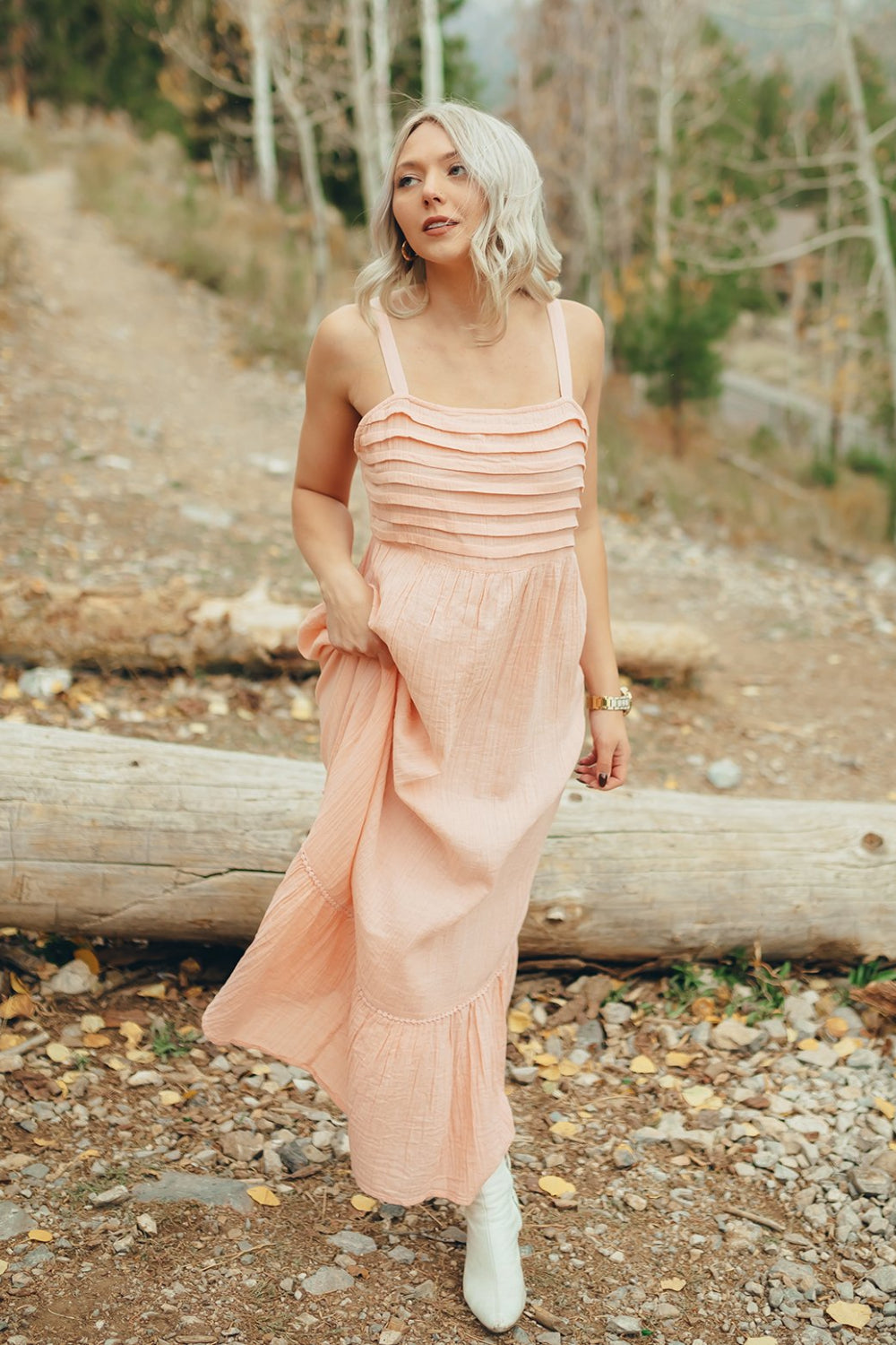 The Rose Dress in Pacific Pink featuring adjustable spaghetti straps, a tiered skirt, and ruffles on the chest, showcasing its elegant design.