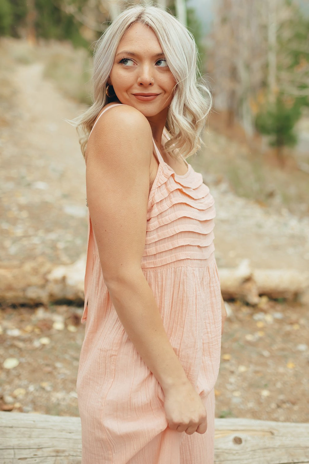 The Rose Dress in Pacific Pink featuring adjustable spaghetti straps, a tiered skirt, and ruffles on the chest, showcasing its elegant design.