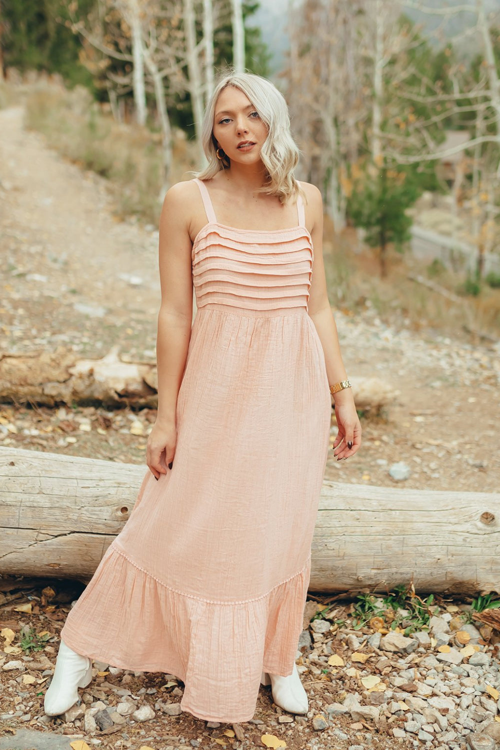 The Rose Dress in Pacific Pink featuring adjustable spaghetti straps, a tiered skirt, and ruffles on the chest, showcasing its elegant design.