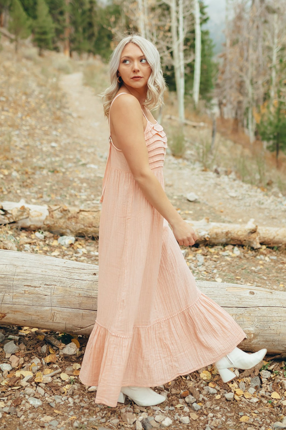 The Rose Dress in Pacific Pink featuring adjustable spaghetti straps, a tiered skirt, and ruffles on the chest, showcasing its elegant design.