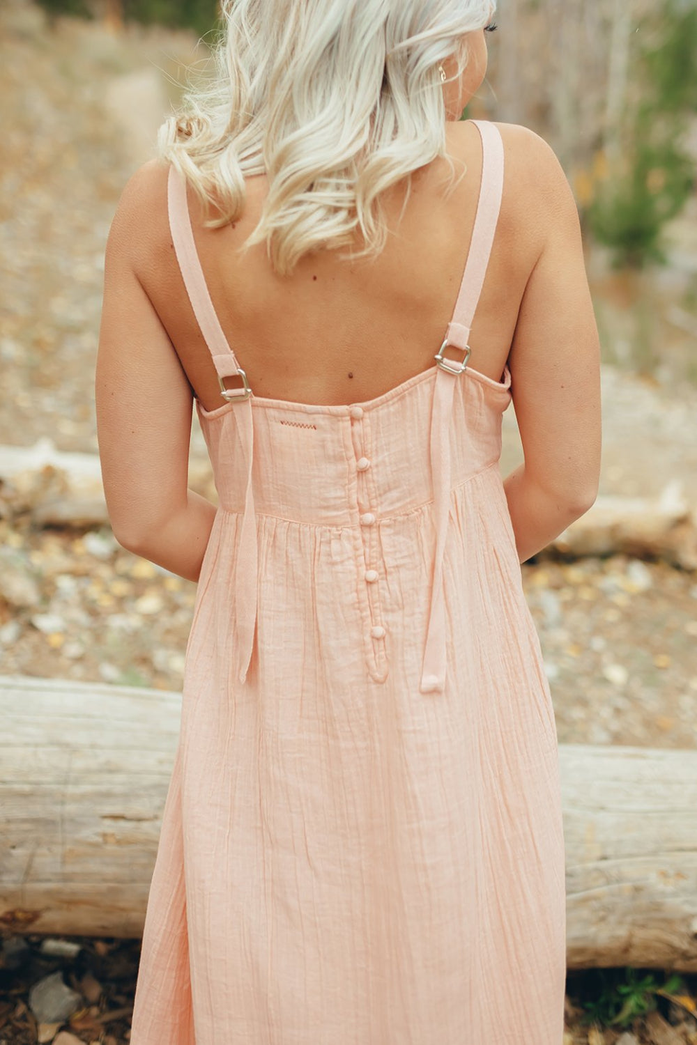 The Rose Dress in Pacific Pink featuring adjustable spaghetti straps, a tiered skirt, and ruffles on the chest, showcasing its elegant design.