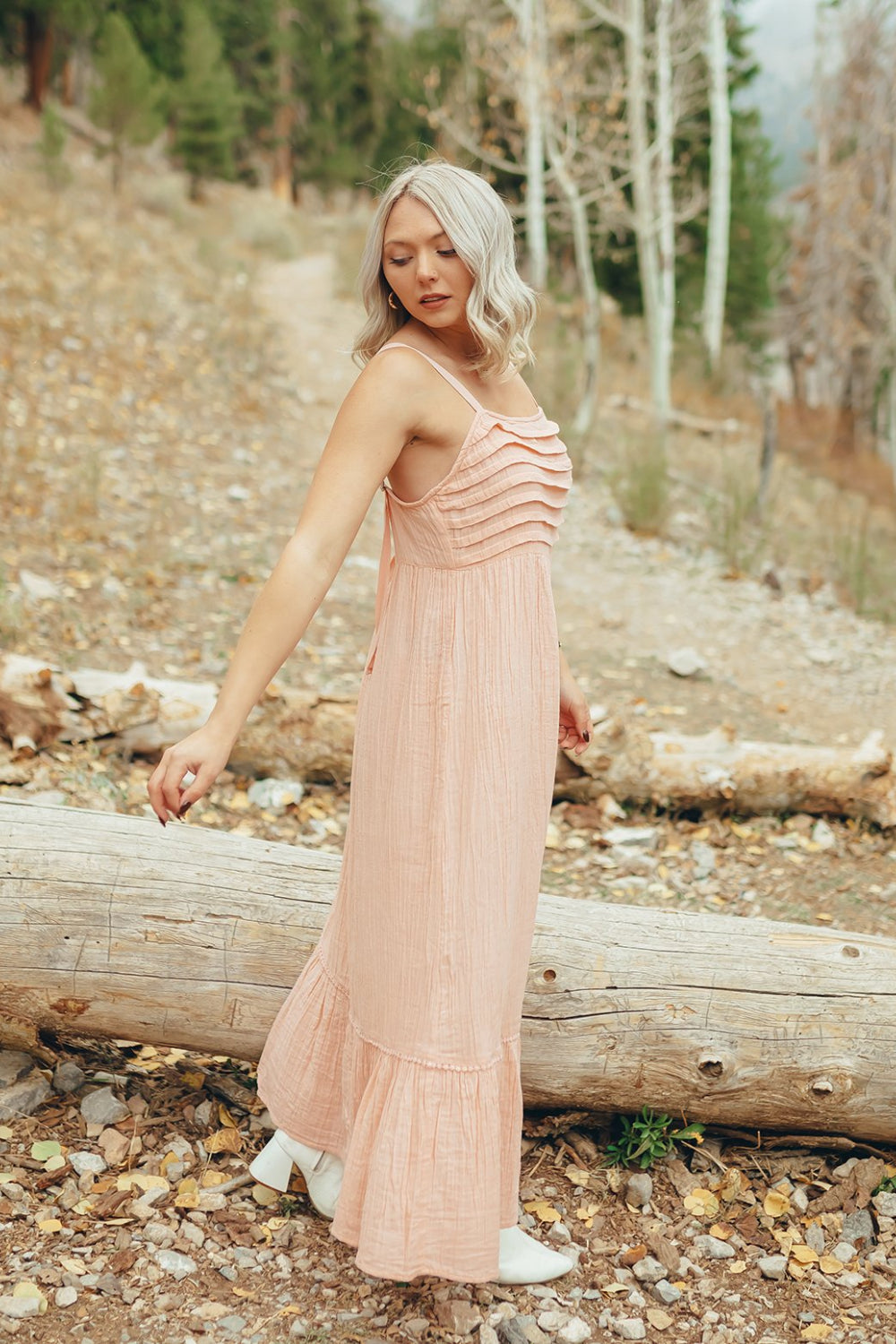 The Rose Dress in Pacific Pink featuring adjustable spaghetti straps, a tiered skirt, and ruffles on the chest, showcasing its elegant design.