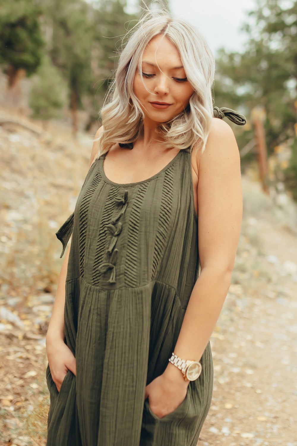 The Saguaro Dress in olive green with spaghetti straps, featuring a maxi length and pockets, perfect for beach outings.