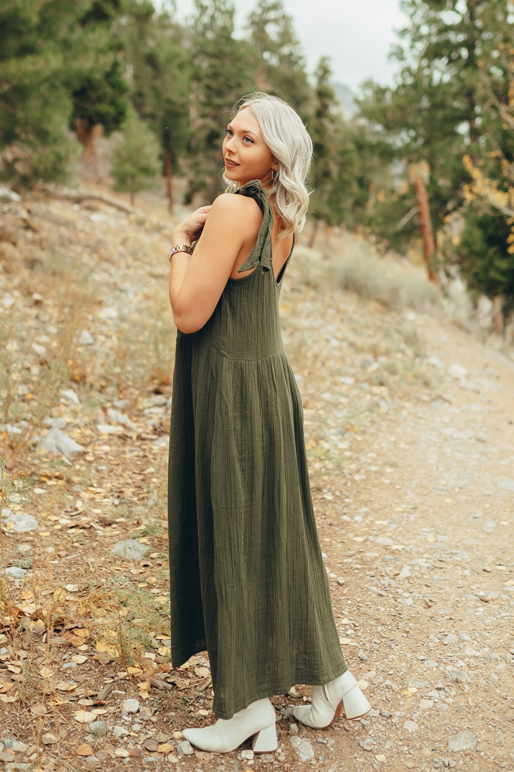 The Saguaro Dress in olive green with spaghetti straps, featuring a maxi length and pockets, perfect for beach outings.