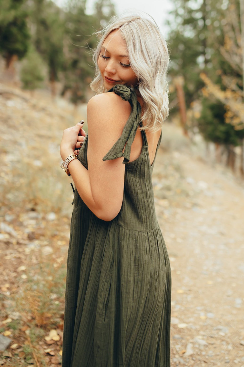 The Saguaro Dress in olive green with spaghetti straps, featuring a maxi length and pockets, perfect for beach outings.