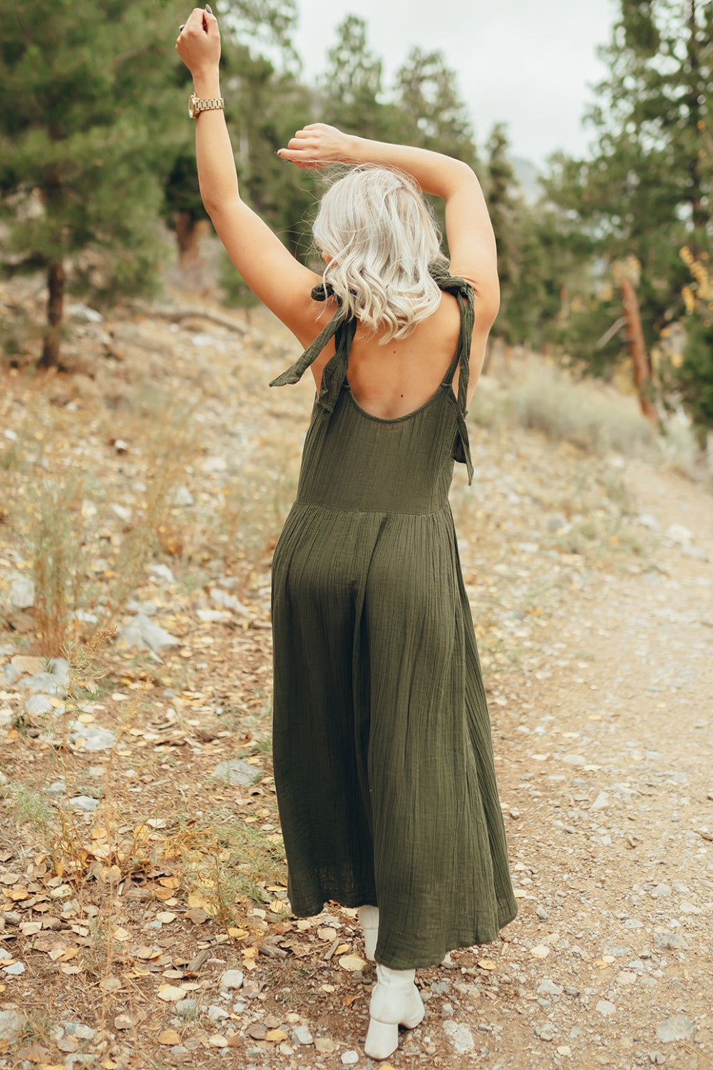 The Saguaro Dress in olive green with spaghetti straps, featuring a maxi length and pockets, perfect for beach outings.