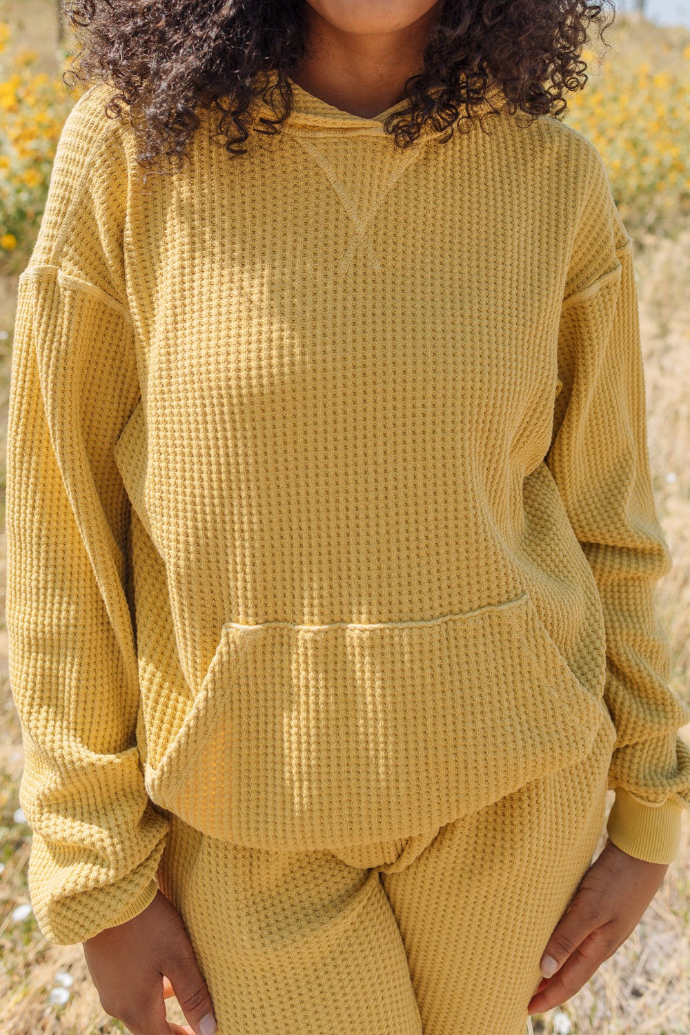 A cozy waffle knit hoodie in a relaxed fit, featuring a drawstring hood, made from 100% organic cotton.