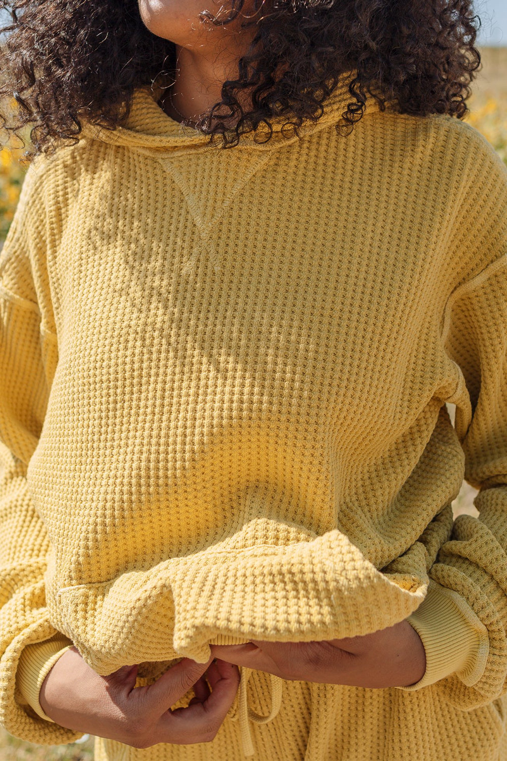 A cozy waffle knit hoodie in a relaxed fit, featuring a drawstring hood, made from 100% organic cotton.