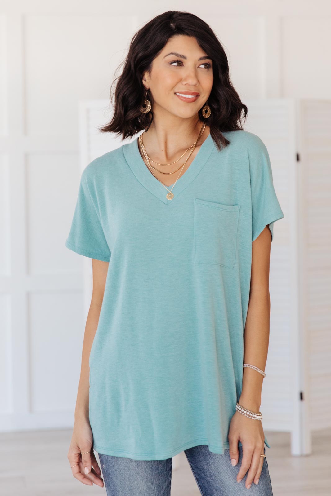 The Weekender Top in Blue, a stylish v-neck t-shirt with a loose fit and long sleeves, featuring a front pocket and split hem.