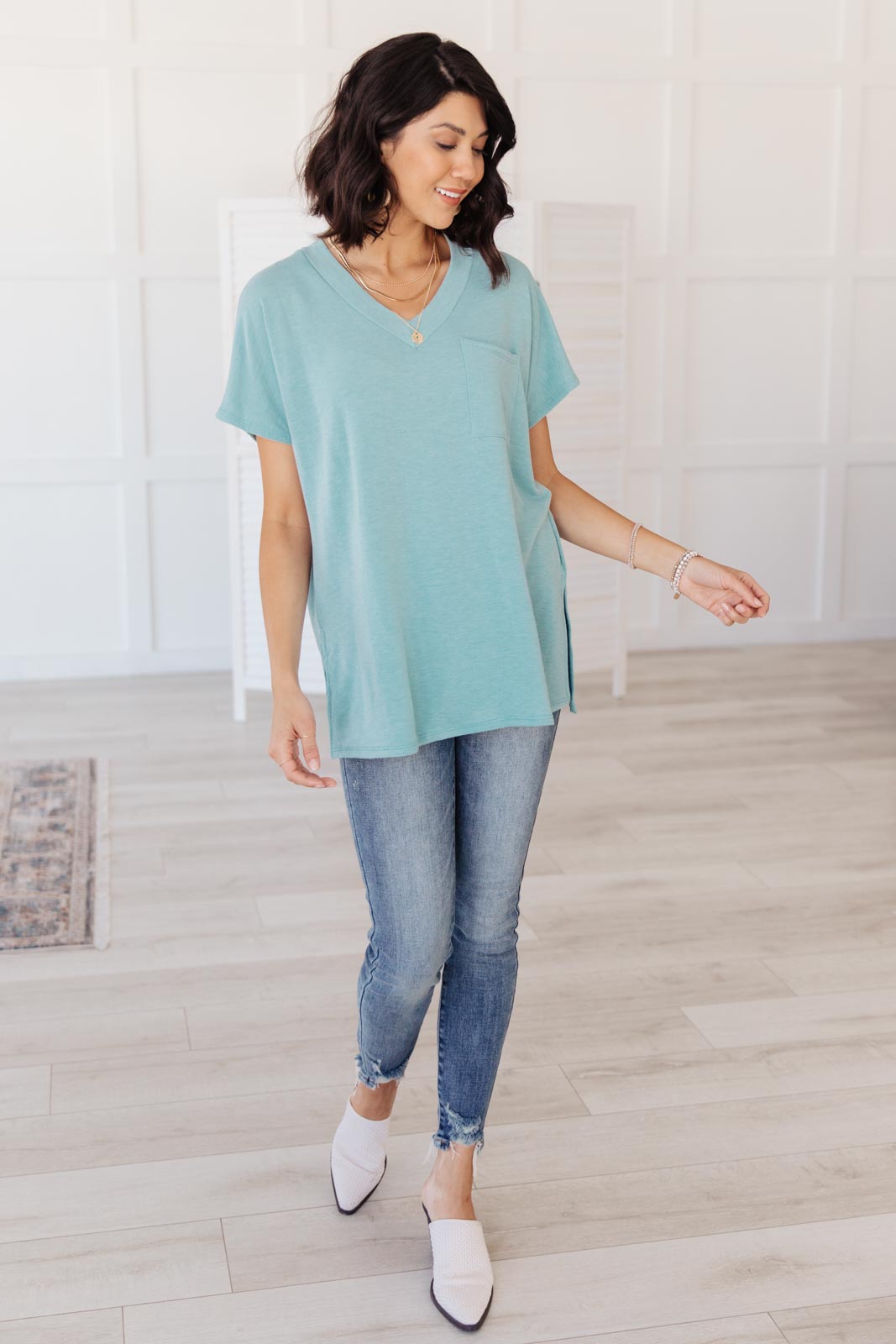 The Weekender Top in Blue, a stylish v-neck t-shirt with a loose fit and long sleeves, featuring a front pocket and split hem.