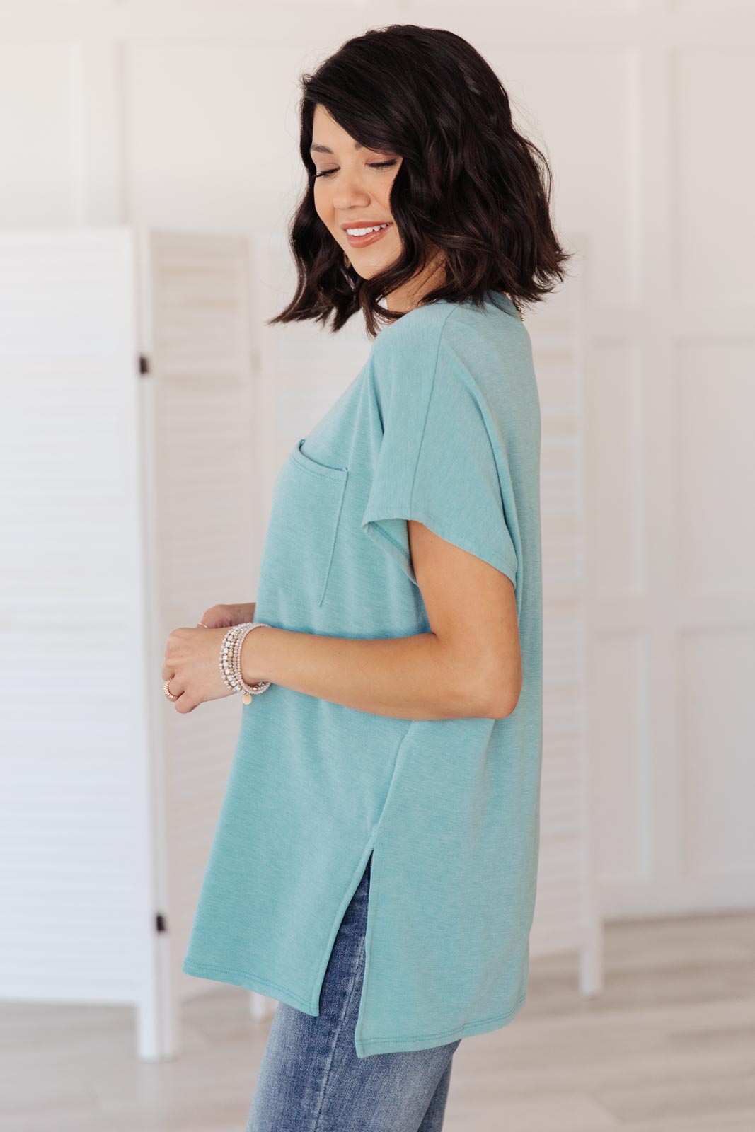 The Weekender Top in Blue, a stylish v-neck t-shirt with a loose fit and long sleeves, featuring a front pocket and split hem.