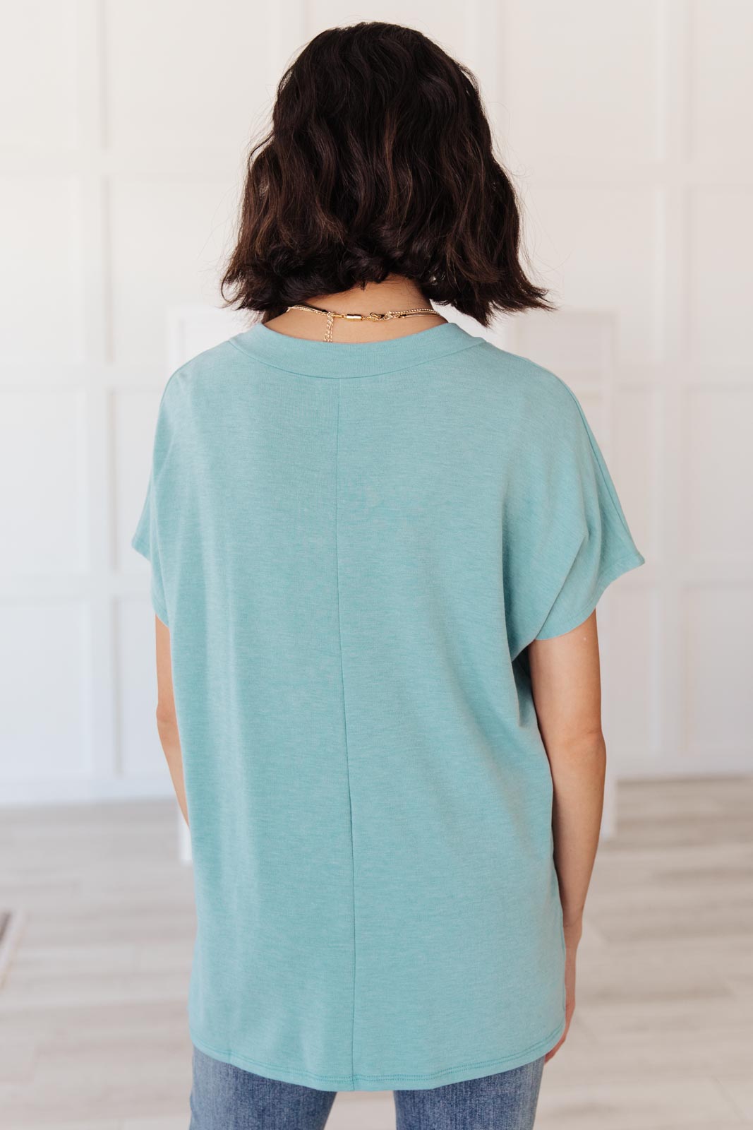 The Weekender Top in Blue, a stylish v-neck t-shirt with a loose fit and long sleeves, featuring a front pocket and split hem.