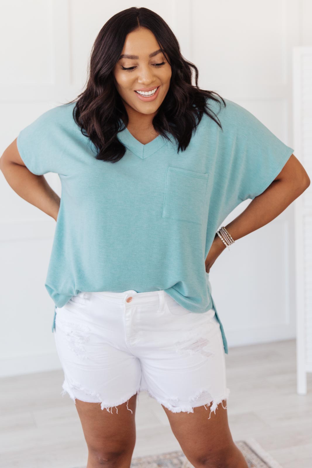 The Weekender Top in Blue, a stylish v-neck t-shirt with a loose fit and long sleeves, featuring a front pocket and split hem.