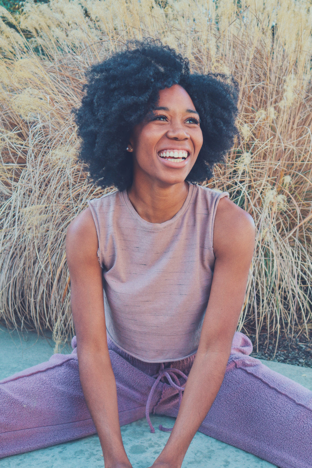 Woman smiling outdoors sitting down.