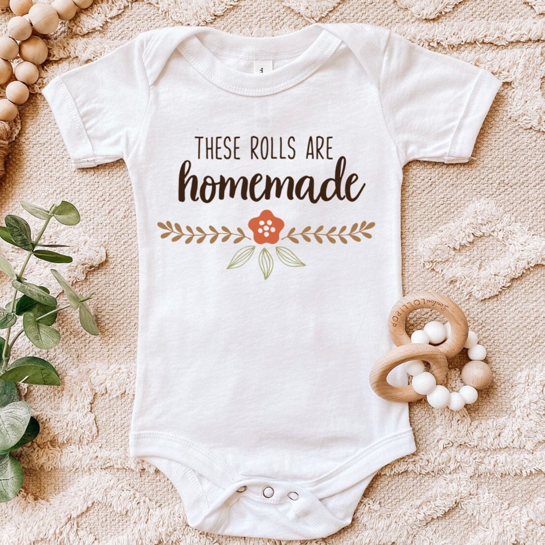 A cute baby wearing a Homemade Rolls Baby Onesie, showcasing its comfy design and vibrant colors.