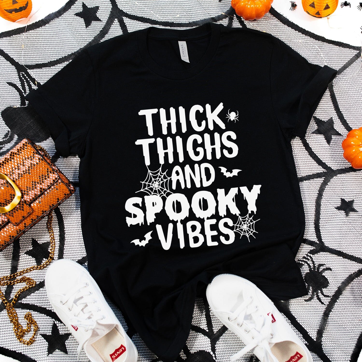 A stylish unisex T-shirt featuring the phrase 'Thick Thighs and Spooky Vibes' in a fun, eye-catching design, perfect for casual wear.