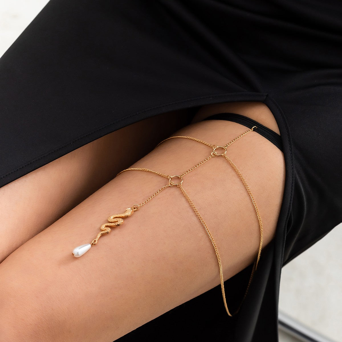 Gold thigh chain featuring a snake-shaped pendant, elegantly designed with fine chains and an elastic band for comfort.