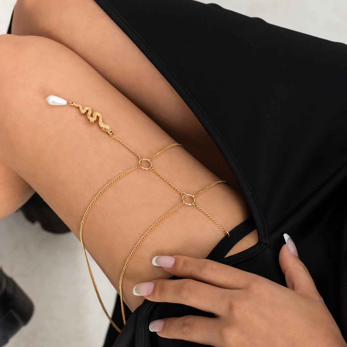 Gold thigh chain featuring a snake-shaped pendant, elegantly designed with fine chains and an elastic band for comfort.