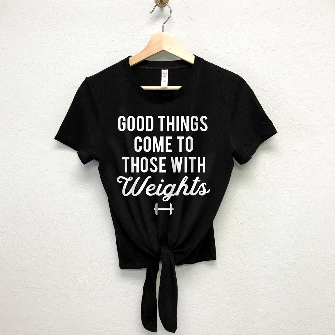 A stylish front tie crop top in black and white, featuring the phrase 'GOOD THINGS COME TO THOSE WITH WEIGHTS' for a motivational workout look.