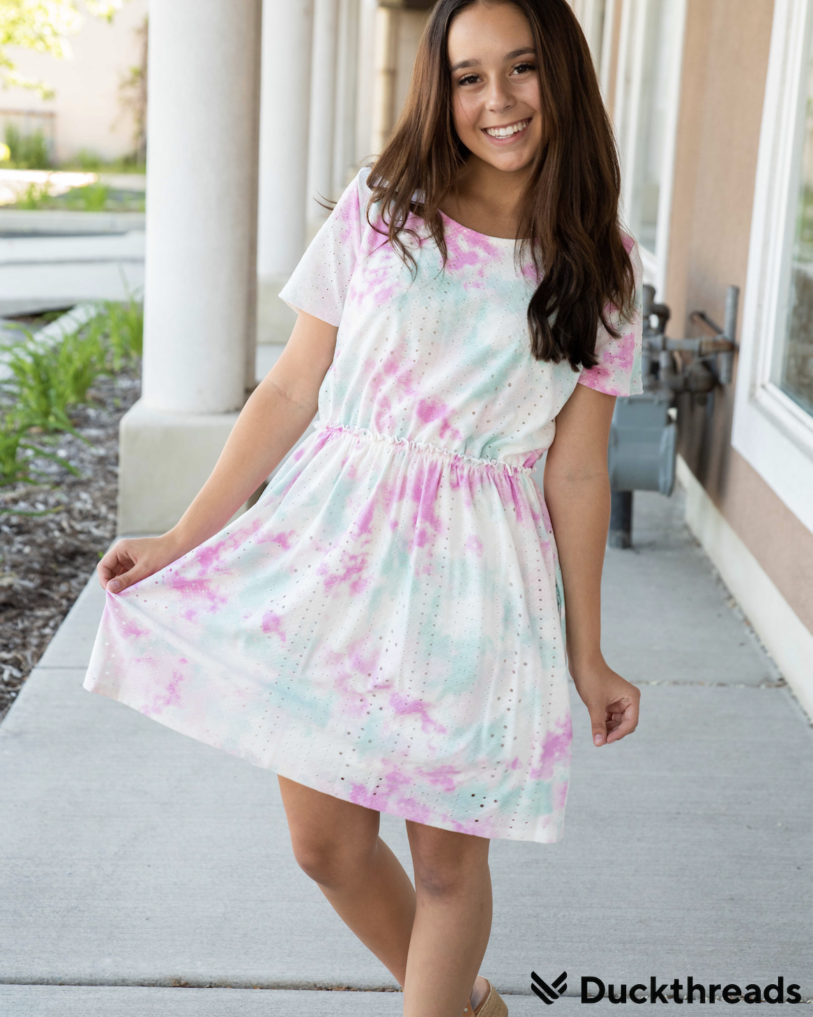 A vibrant Tie Dye Eyelet Dress in Teal and Pink, featuring an elastic waistband and pockets, perfect for summer outings.