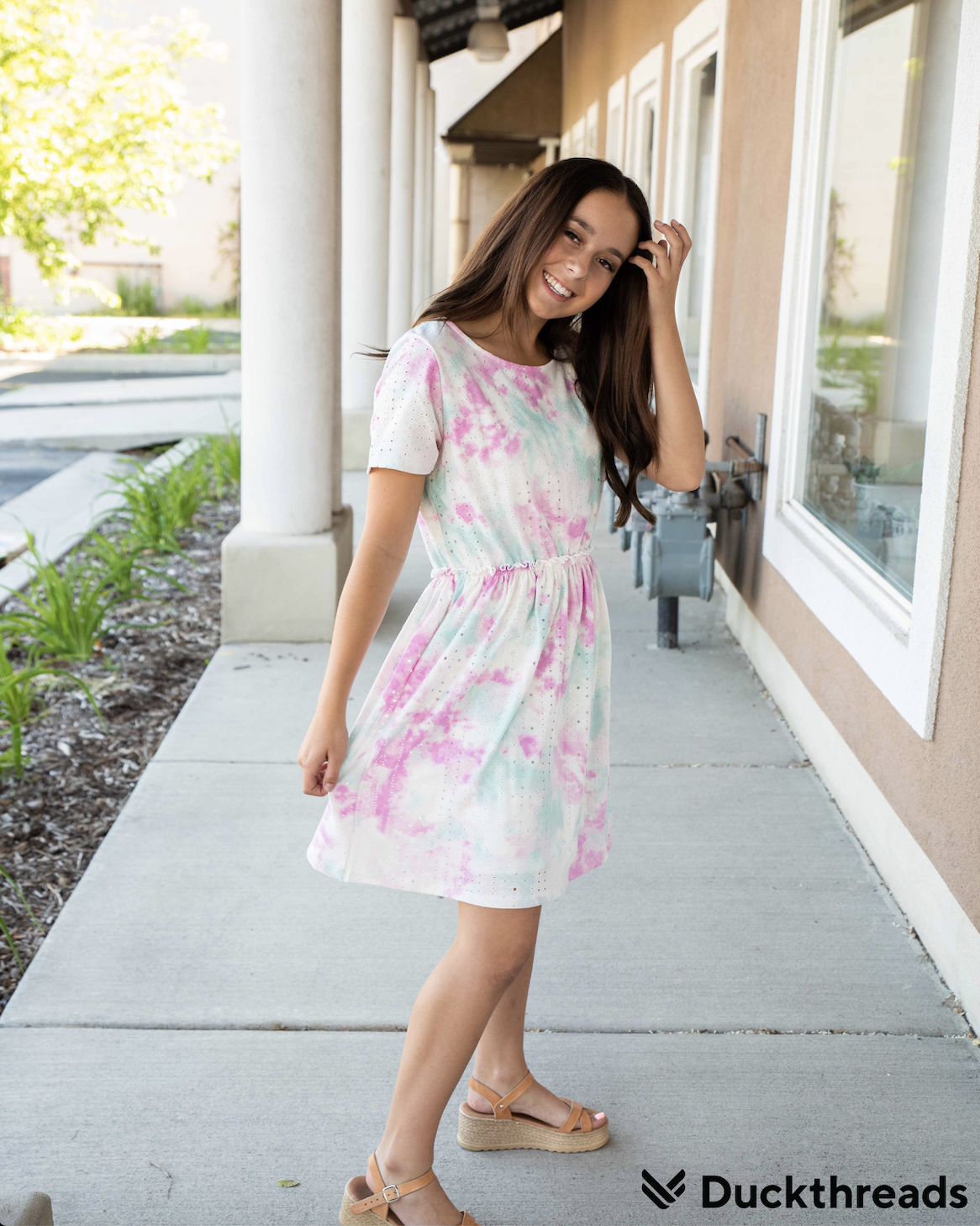 A vibrant Tie Dye Eyelet Dress in Teal and Pink, featuring an elastic waistband and pockets, perfect for summer outings.