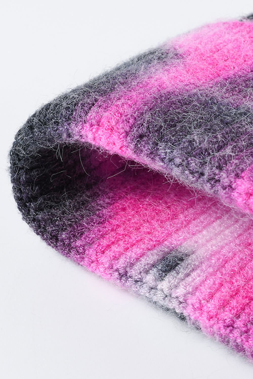 A colorful tie-dye cuffed knit beanie displayed in a flat lay style, showcasing its vibrant patterns and soft texture.