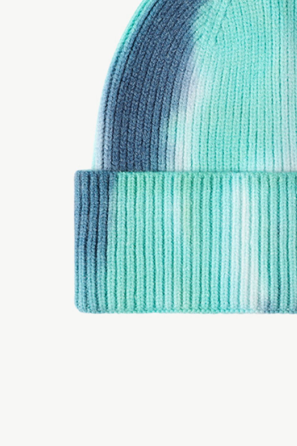 A colorful tie-dye cuffed knit beanie displayed in a flat lay style, showcasing its vibrant patterns and soft texture.