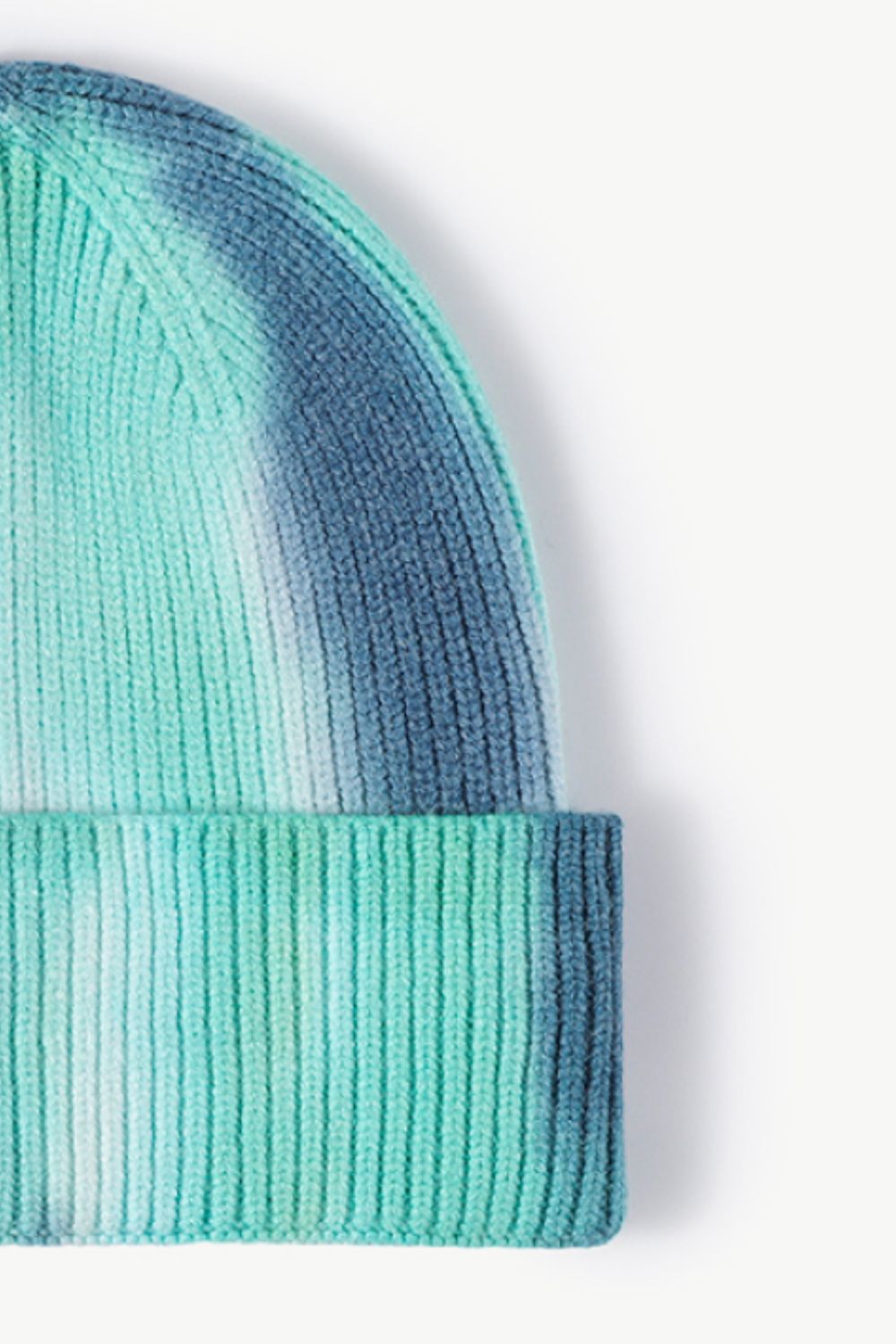 A colorful tie-dye cuffed knit beanie displayed in a flat lay style, showcasing its vibrant patterns and soft texture.