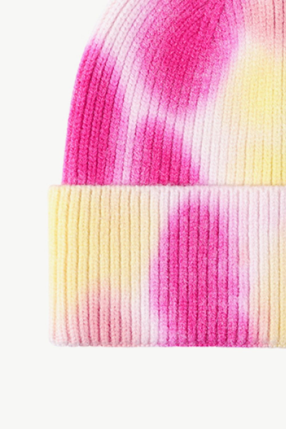 A colorful tie-dye cuffed knit beanie displayed in a flat lay style, showcasing its vibrant patterns and soft texture.