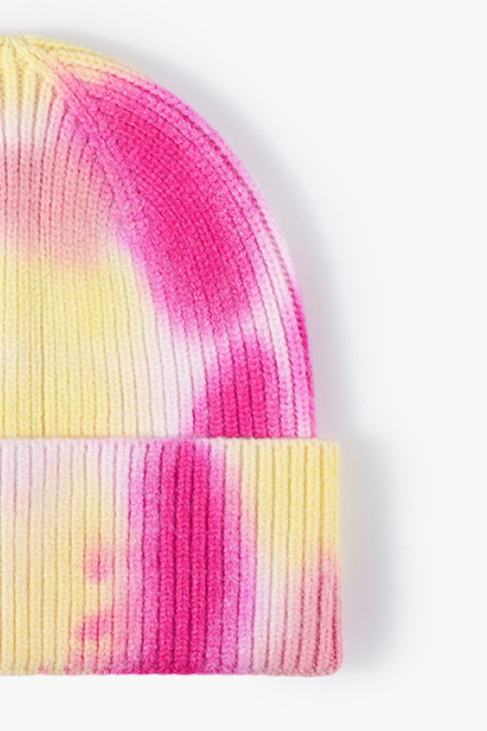 A colorful tie-dye cuffed knit beanie displayed in a flat lay style, showcasing its vibrant patterns and soft texture.