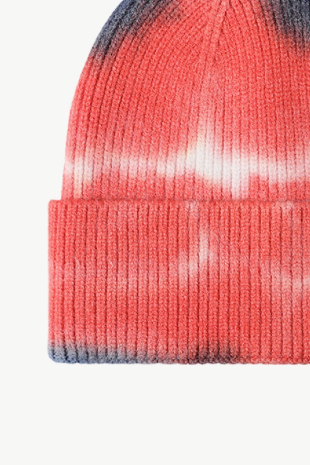 A colorful tie-dye cuffed knit beanie displayed in a flat lay style, showcasing its vibrant patterns and soft texture.