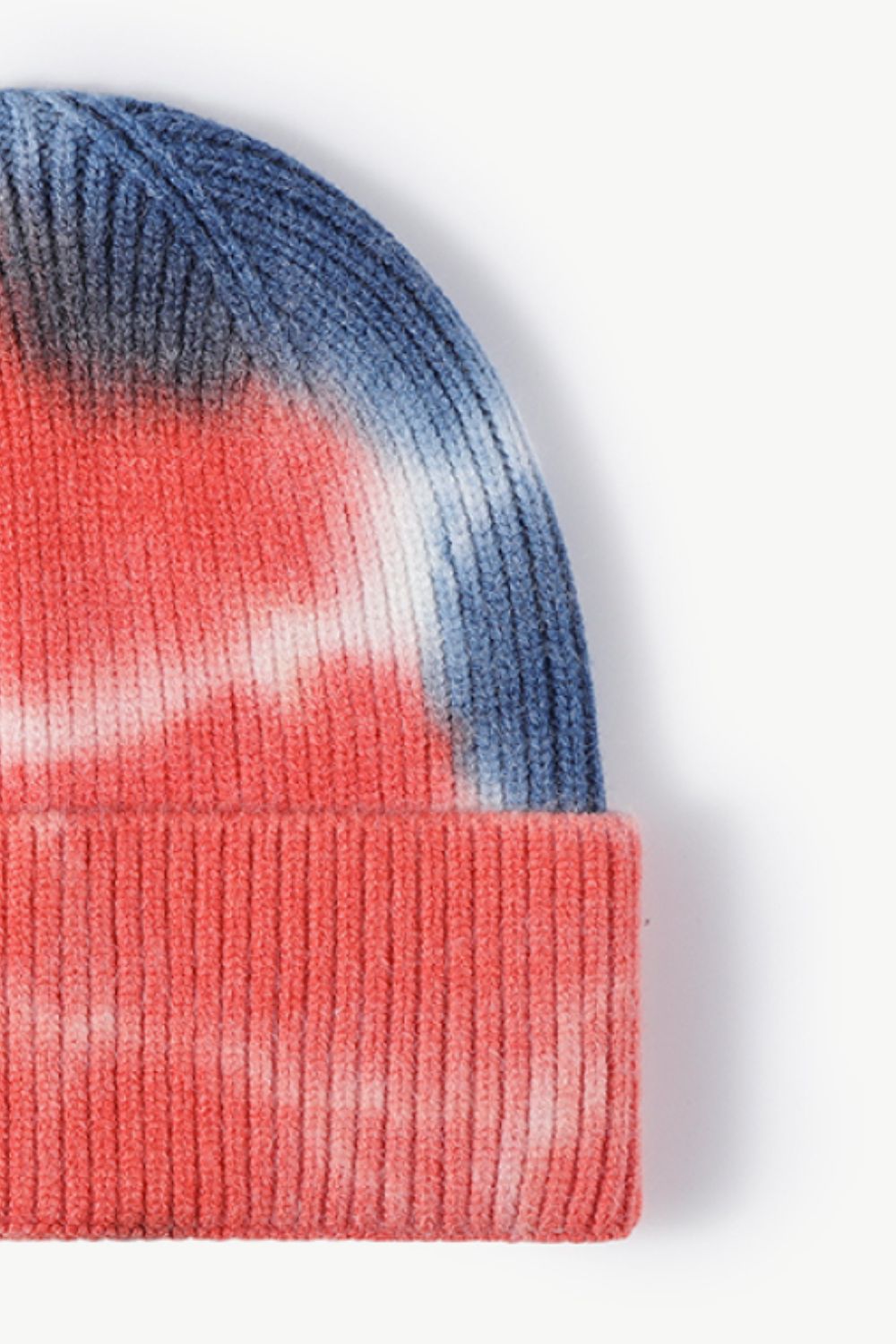 A colorful tie-dye cuffed knit beanie displayed in a flat lay style, showcasing its vibrant patterns and soft texture.