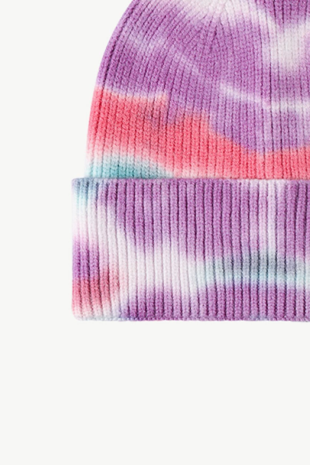 A colorful tie-dye cuffed knit beanie displayed in a flat lay style, showcasing its vibrant patterns and soft texture.