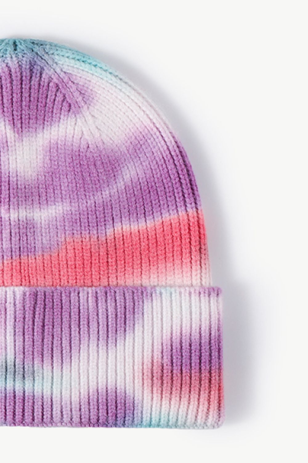 A colorful tie-dye cuffed knit beanie displayed in a flat lay style, showcasing its vibrant patterns and soft texture.