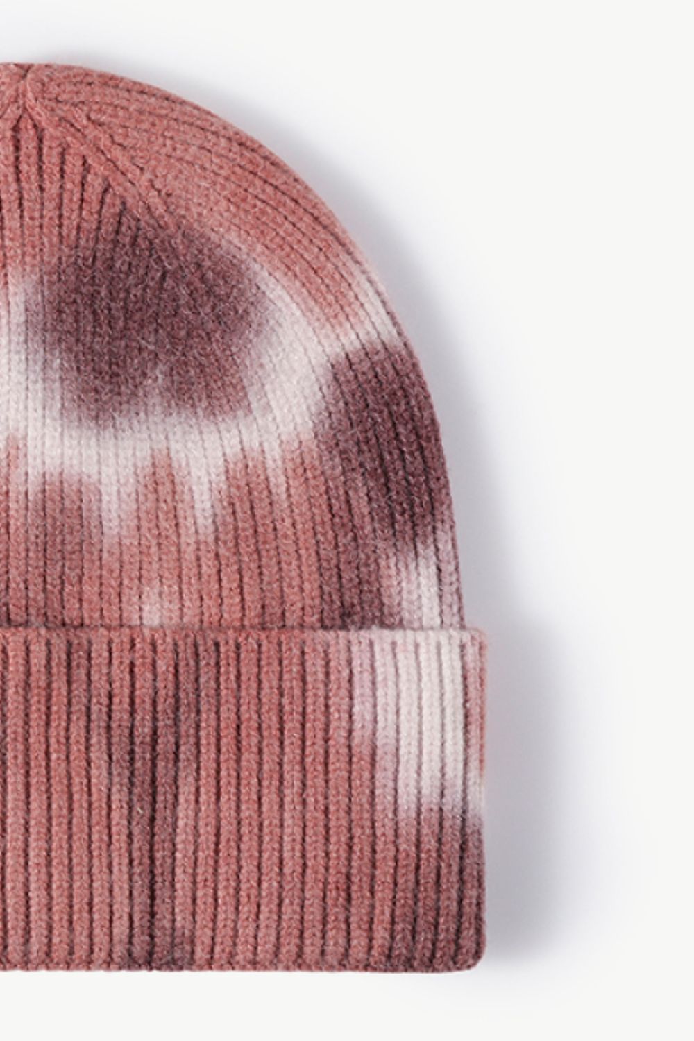 A colorful tie-dye cuffed knit beanie displayed in a flat lay style, showcasing its vibrant patterns and soft texture.