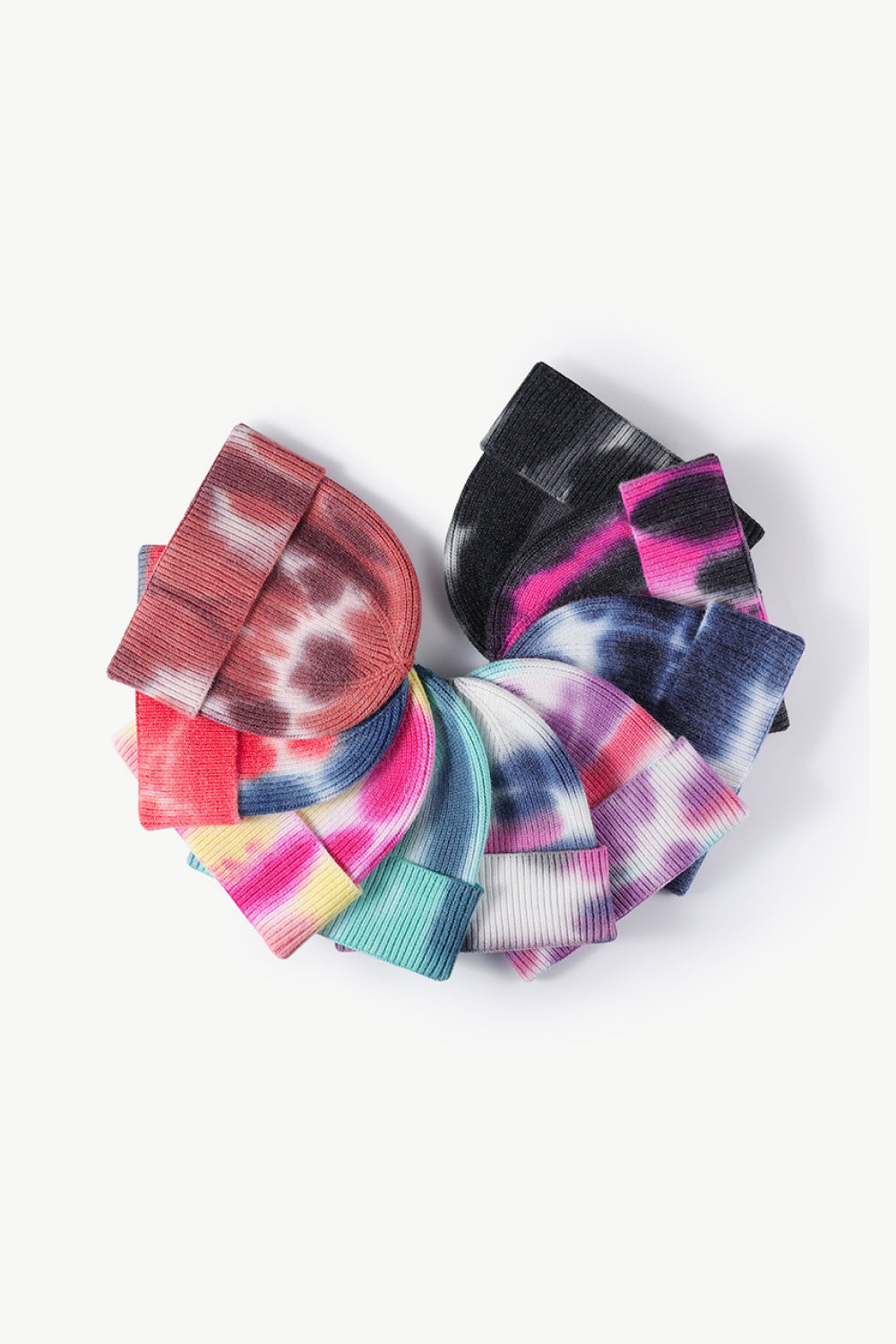 A colorful tie-dye cuffed knit beanie displayed in a flat lay style, showcasing its vibrant patterns and soft texture.