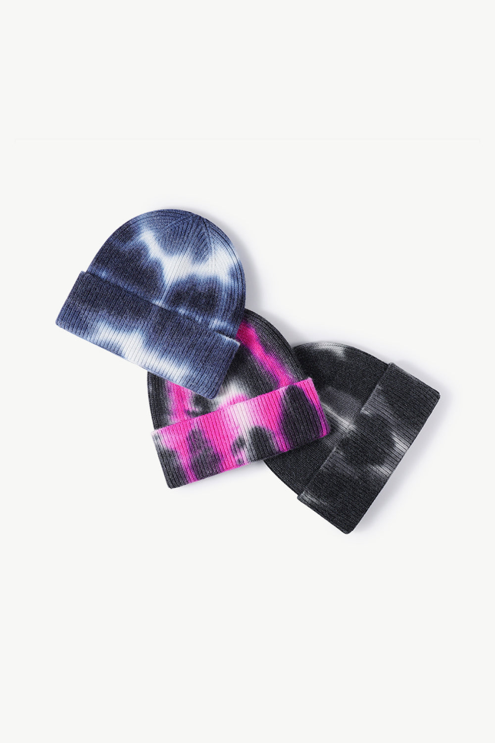 A colorful tie-dye cuffed knit beanie displayed in a flat lay style, showcasing its vibrant patterns and soft texture.