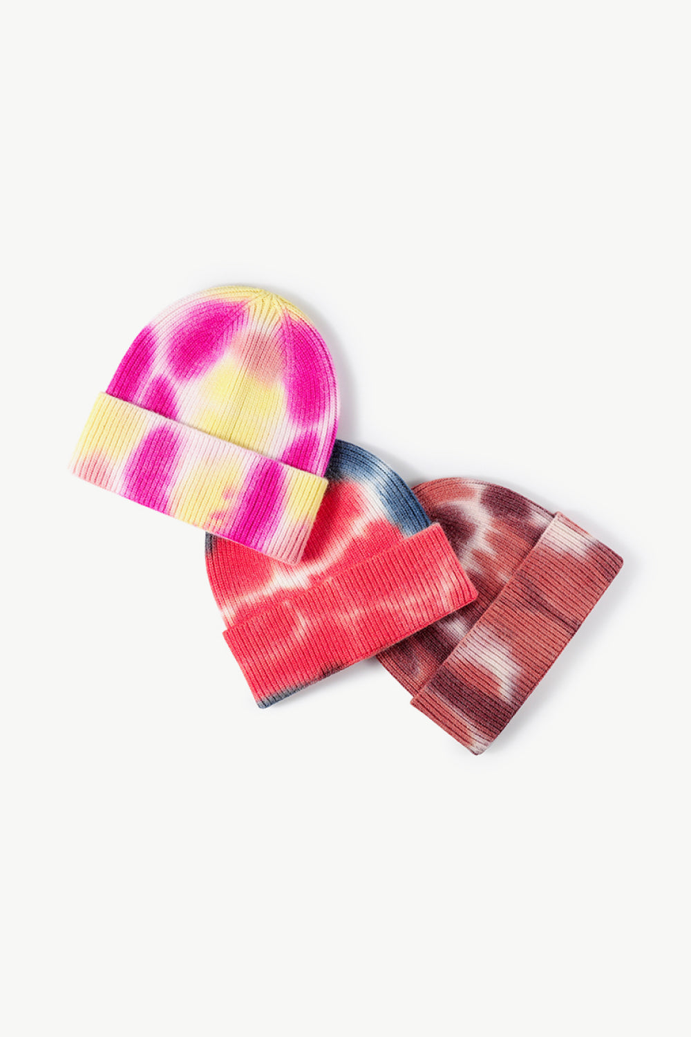 A colorful tie-dye cuffed knit beanie displayed in a flat lay style, showcasing its vibrant patterns and soft texture.