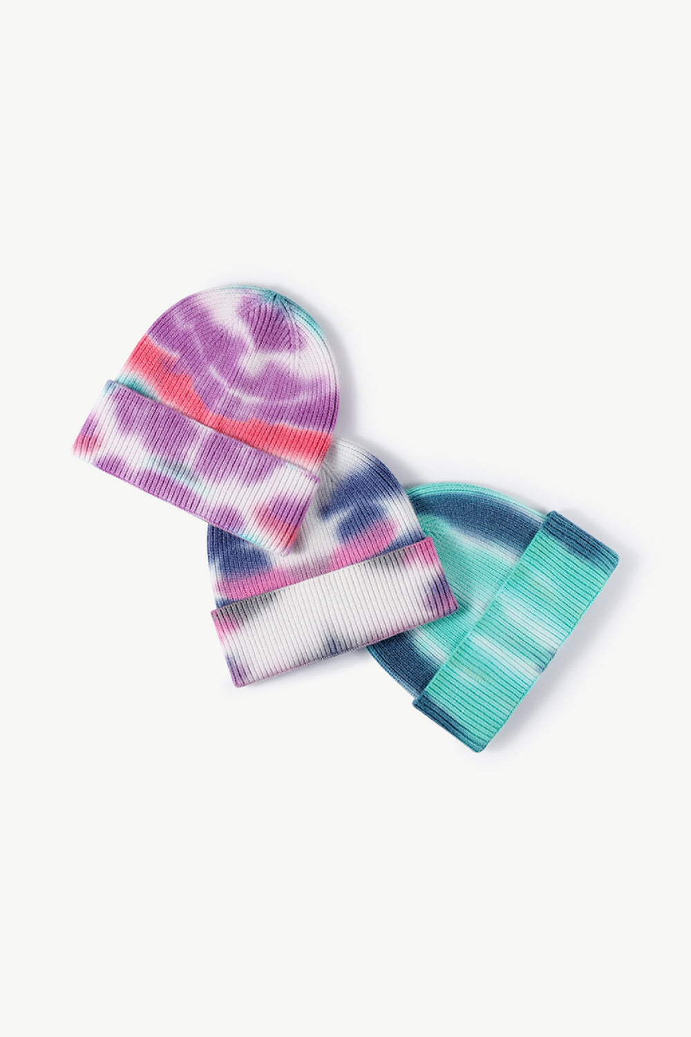 A colorful tie-dye cuffed knit beanie displayed in a flat lay style, showcasing its vibrant patterns and soft texture.