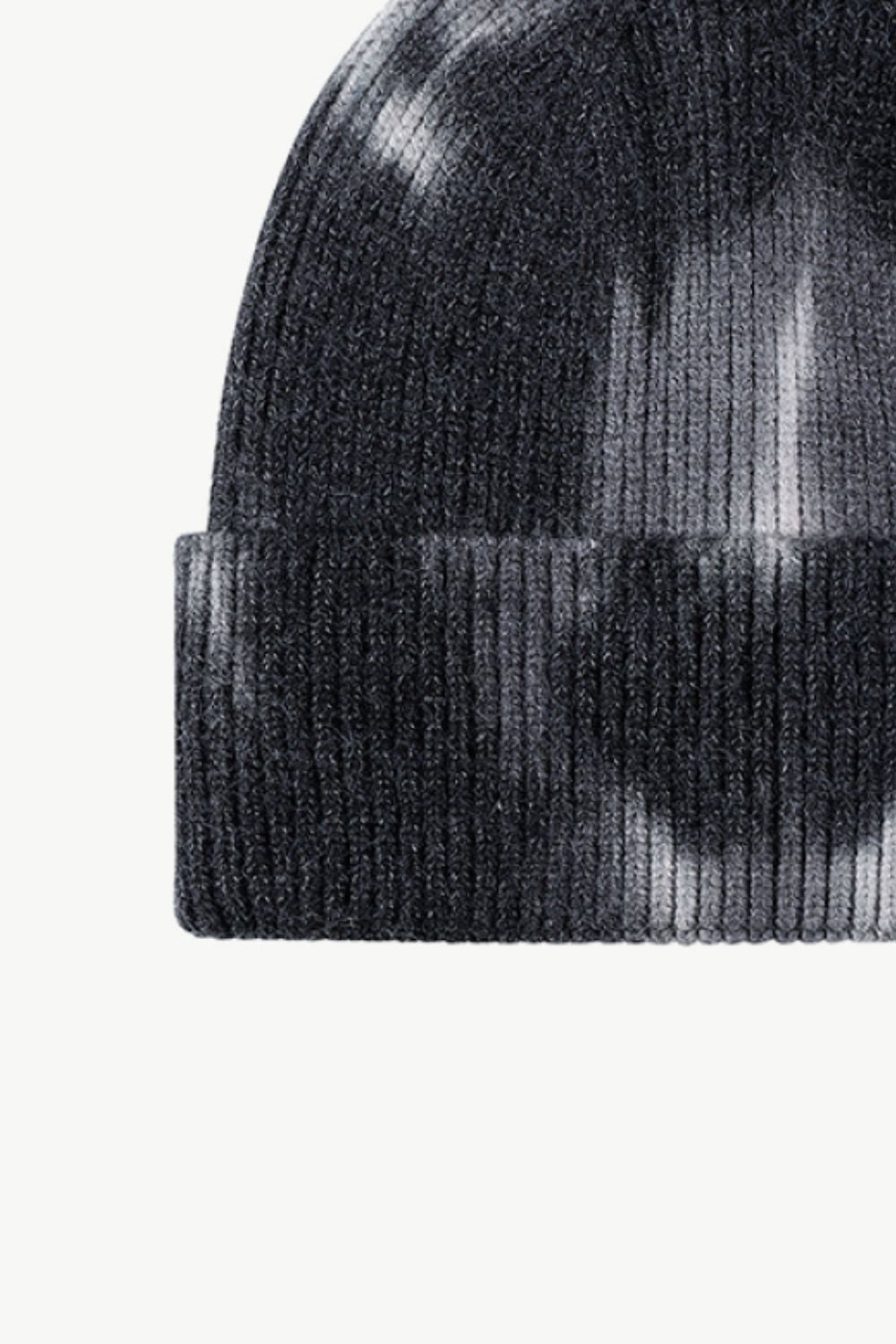 A colorful tie-dye cuffed knit beanie displayed in a flat lay style, showcasing its vibrant patterns and soft texture.