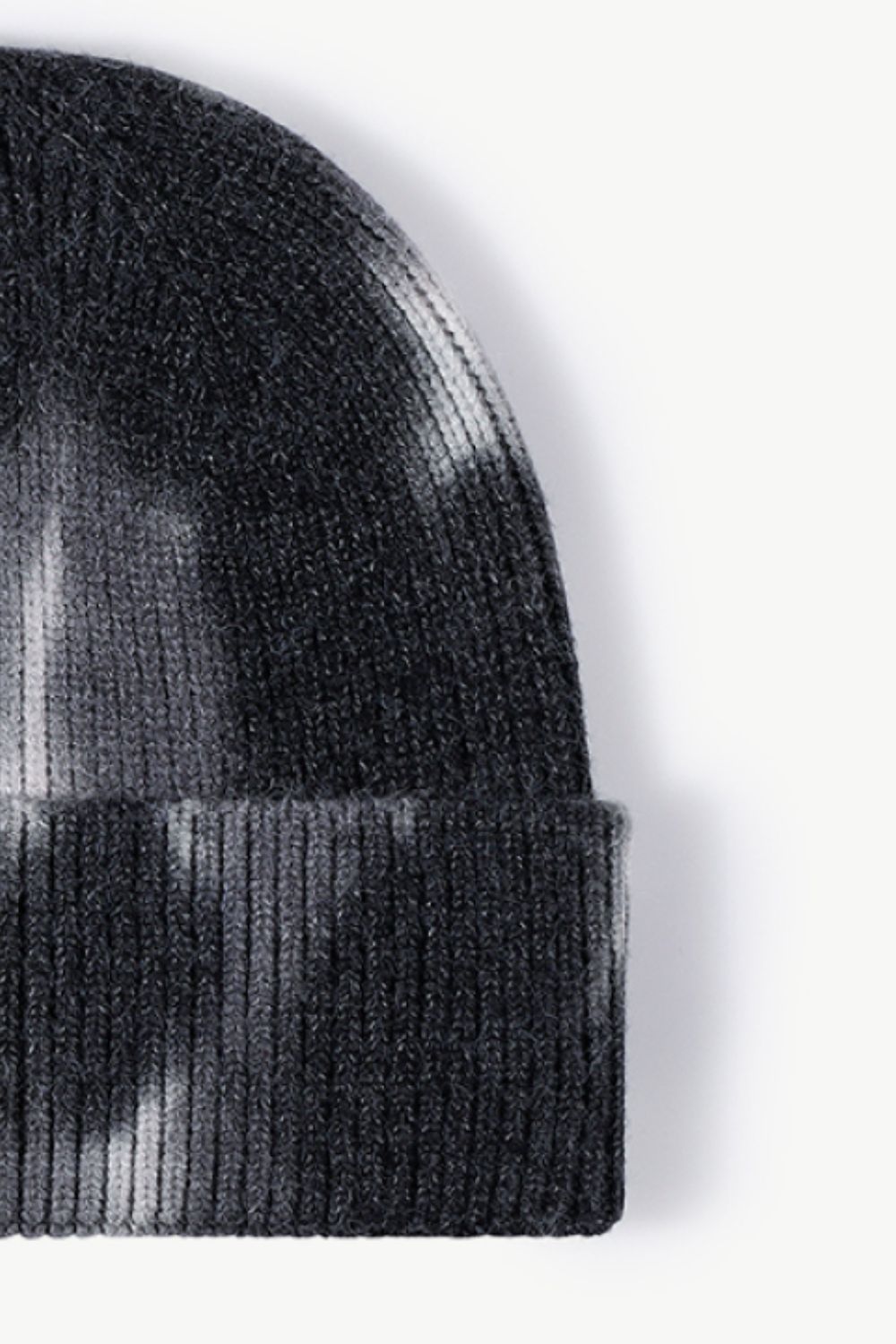 A colorful tie-dye cuffed knit beanie displayed in a flat lay style, showcasing its vibrant patterns and soft texture.