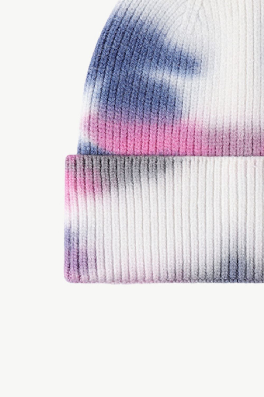 A colorful tie-dye cuffed knit beanie displayed in a flat lay style, showcasing its vibrant patterns and soft texture.