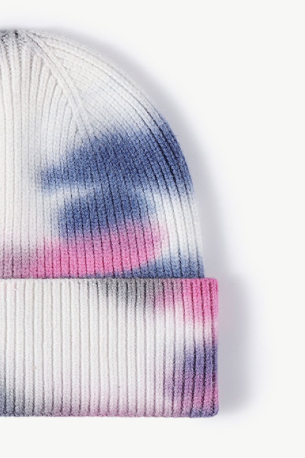 A colorful tie-dye cuffed knit beanie displayed in a flat lay style, showcasing its vibrant patterns and soft texture.