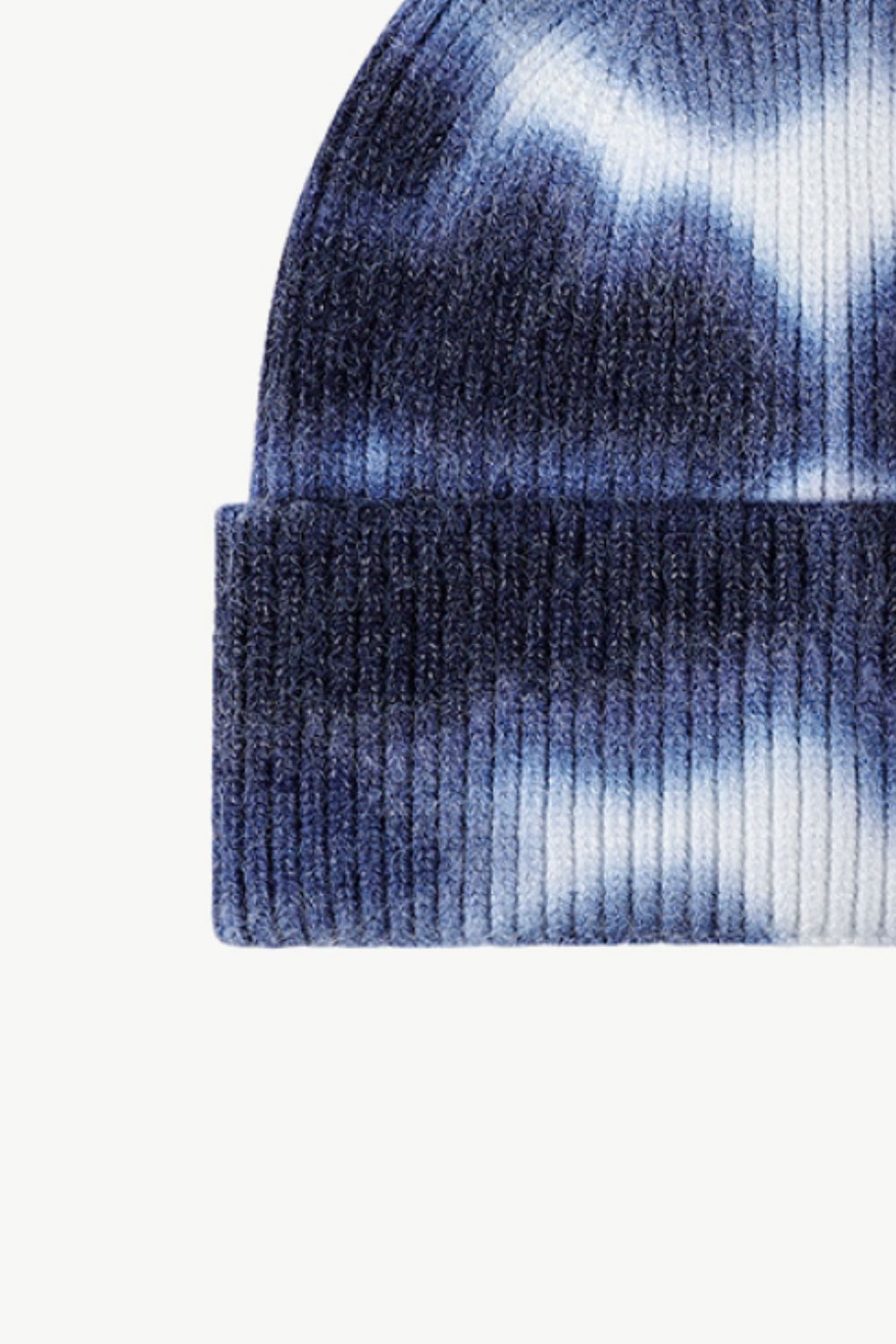 A colorful tie-dye cuffed knit beanie displayed in a flat lay style, showcasing its vibrant patterns and soft texture.