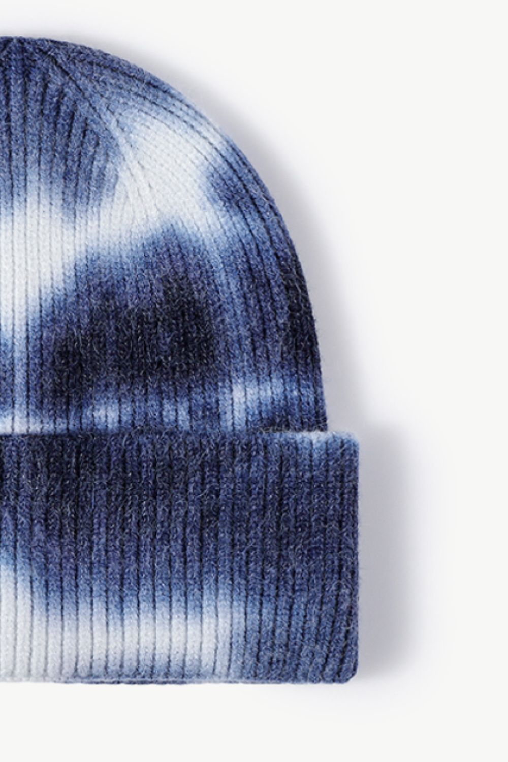 A colorful tie-dye cuffed knit beanie displayed in a flat lay style, showcasing its vibrant patterns and soft texture.